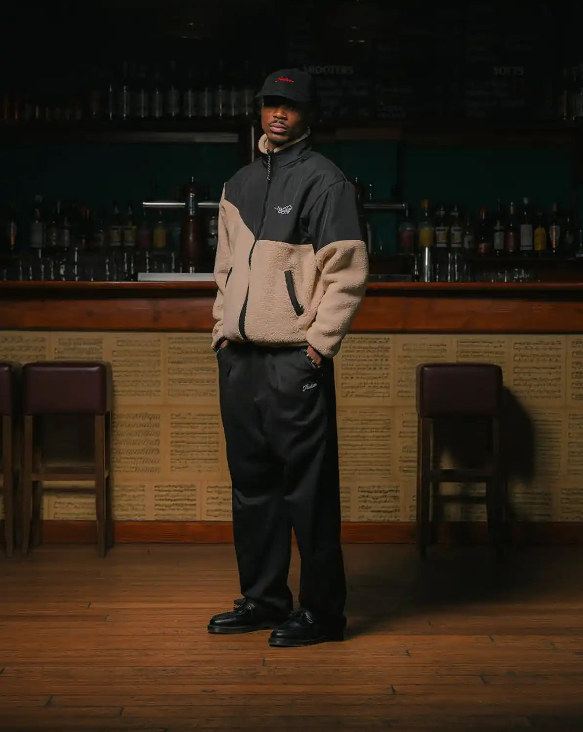 Veste en polaire bicolore avec un pantalon noir et un chapeau seau.