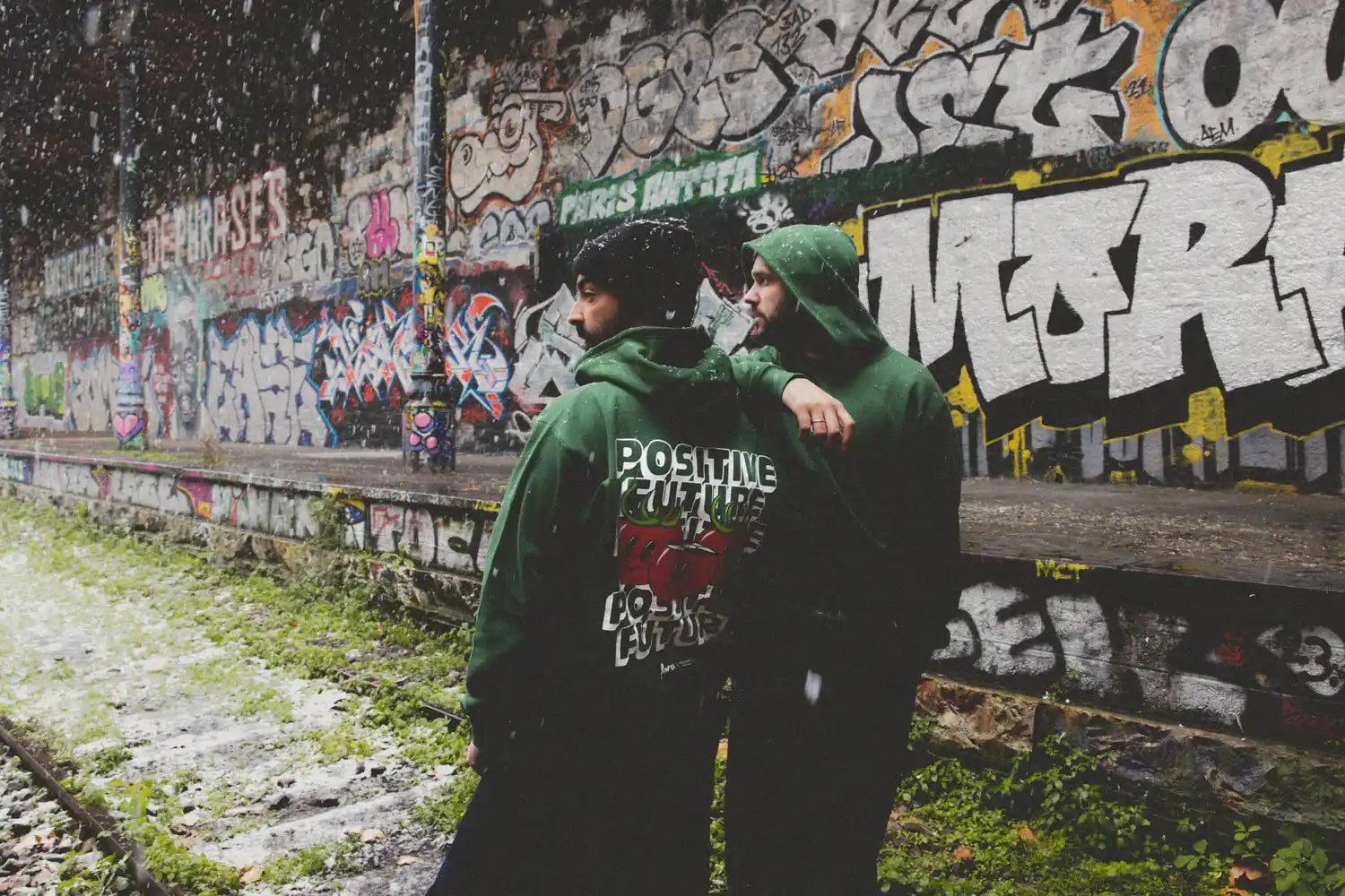 Hoodie vert avec du texte devant un arrière-plan de graffiti.