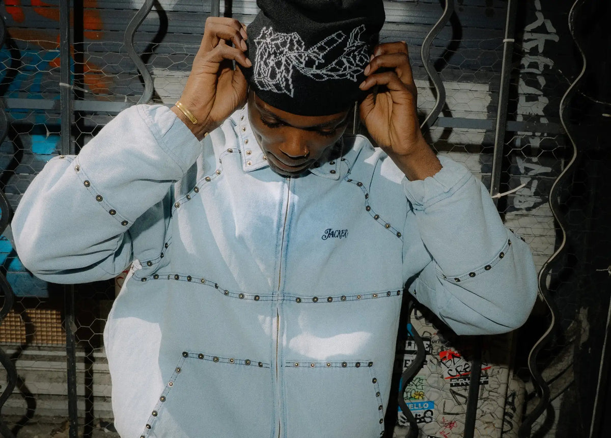 Veste en jean bleu clair avec des clous noirs et un petit logo brodé sur la poitrine.